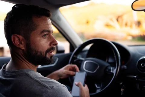 Young man using phone waiting sitting inside car Stock Photos