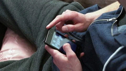 Young man using phone while sitting at home Stock Footage 74980574