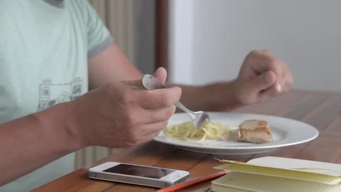 Young man using phone while eating breakfast Stock-Footage 84787925