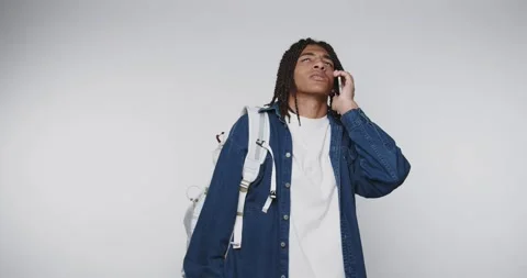 Young man using a phone while expressing surprise in a studio setting durin.. Vídeo Stock 328248608
