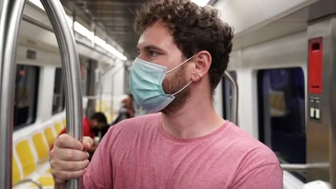 Young man using public transportation stands inside of a train wearing a surg Stockbeeldmateriaal 133062656