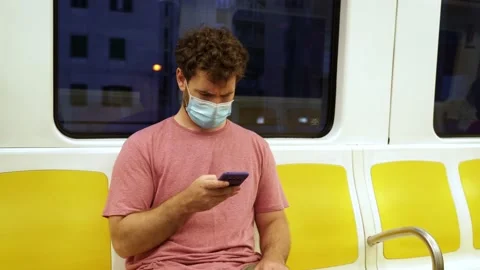 Young man using public transportation sits inside of a train wearing a surgic Video stock 133062694