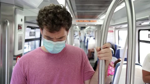 Young man using public transportation stands inside of a train wearing a surg Stock Footage 133062728