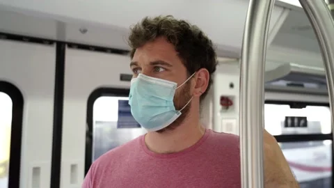 Young man using public transportation stands inside of a train wearing a surg Stockbeeldmateriaal 133062756