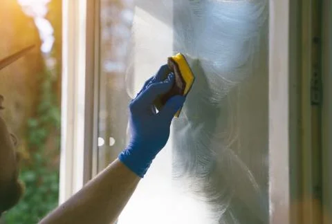Young man is using a rag and squeegee while cleaning windows. Foto stock