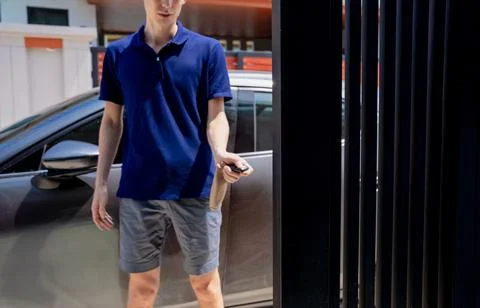 Young man using remote control to open automatic sliding front gate at modern 스톡 사진