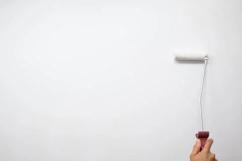 A young man using roller painting white wall with white paint Stock Photos