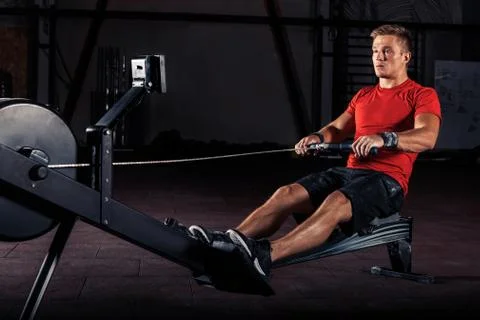 Young man using rowing machine in the gym Stock Photos