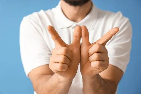 Young man using sign language on blue background, closeup Stock Photos