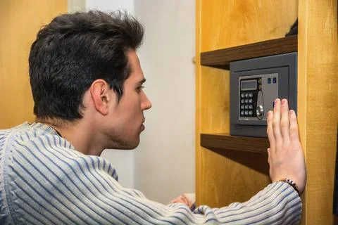 Young man using a small vault in his home Young handsome man using a small... Stockfoto's