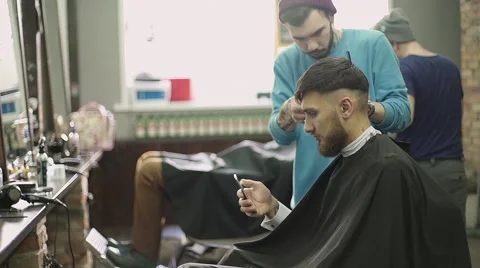Young man using a smart phone in barber shop Stock Footage 56576287