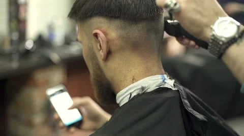 Young man using a smart phone in barber shop Stock Footage 56576324