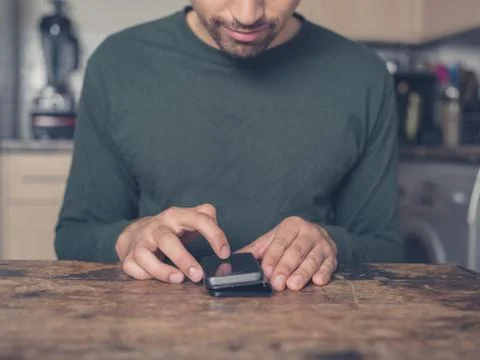 Young man using smart phone in kitchen Stock Photos