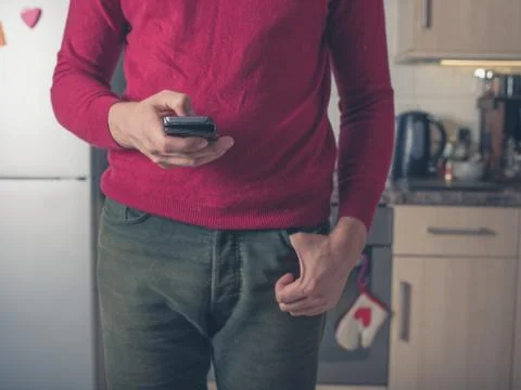 Young man using smart phone in kitchen Stock Photos
