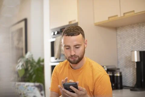 Young man using smart phone in kitchen 스톡 사진