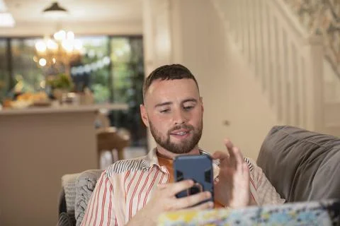 Young man using smart phone on sofa 스톡 사진