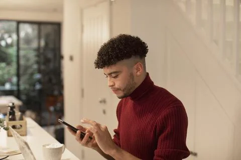 Young man using smart phone in kitchen Stock Photos