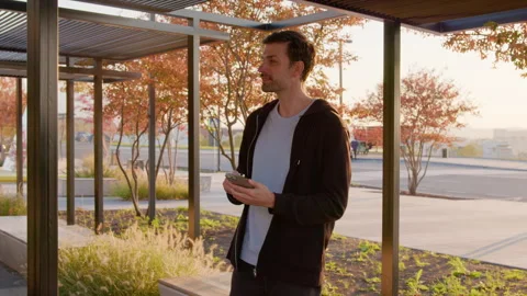 Young man using smartphone to access carsharing service while standing under Stock Footage 317702705