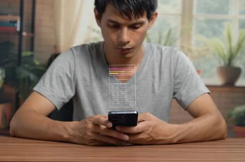 Young man using smartphone to analyze data chart at home workspace Foto stock