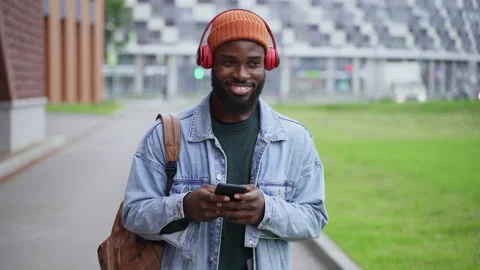Young man using smartphone and smiling while standing on city street in autumn Stock Footage 162225195