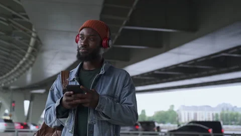 Young man using smartphone and listening to music while standing on city street Stock Footage 163815483