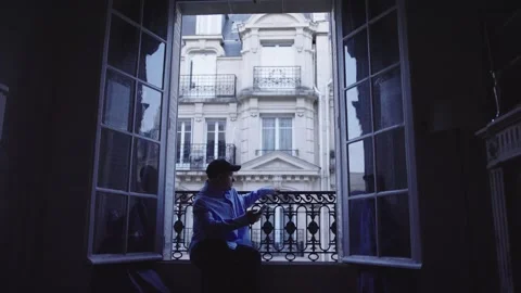 Young man using smartphone and reading book on parisian balcony Stock Footage 312998896