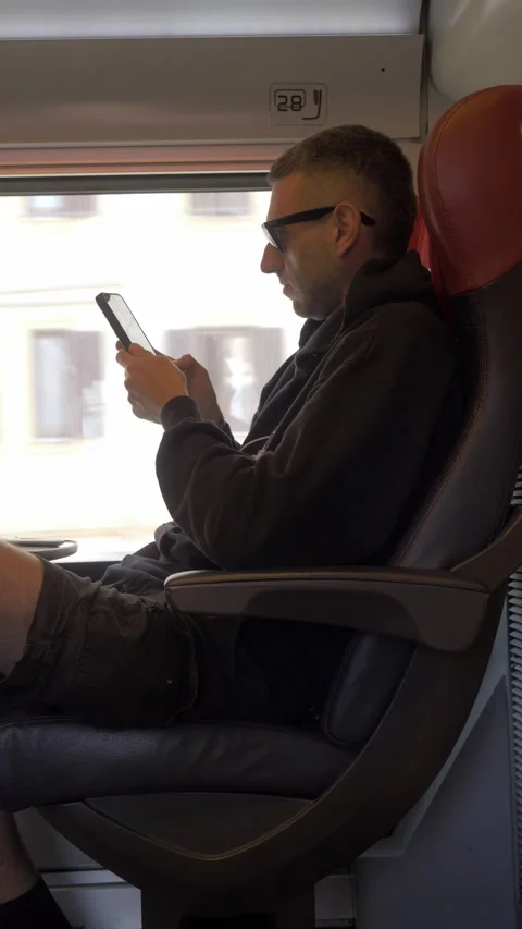 Young man using smartphone and taking photos during train journey 動画素材 334775643