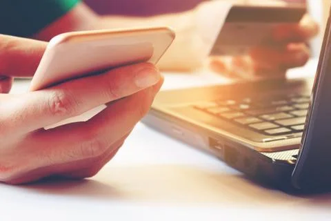 Young man using smartphone and holding credit card with laptop for searchin.. Stock Photos
