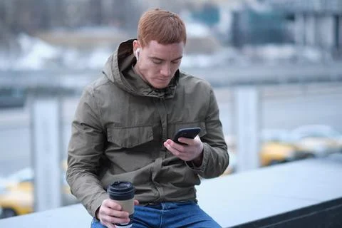 Young man using smartphone and listens to music in bluetooth headphones. lonely 스톡 사진