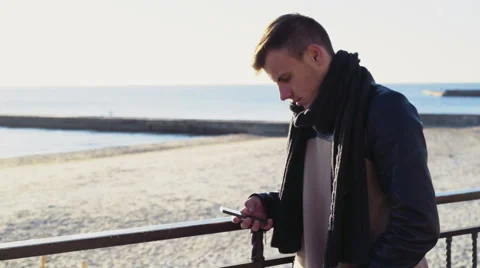 Young man using a smartphone on the autumn beach Stock Footage 57295892