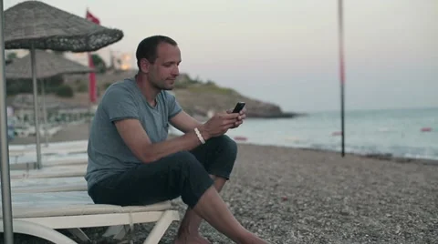 Young man using smartphone on the beach HD Stock Footage