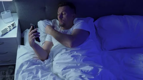 Young man using smartphone in bed at night. Insomnia and sleep problems conce Stock Footage 289562007
