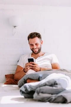 Young man using smartphone in the bed in the morning Stock Photos