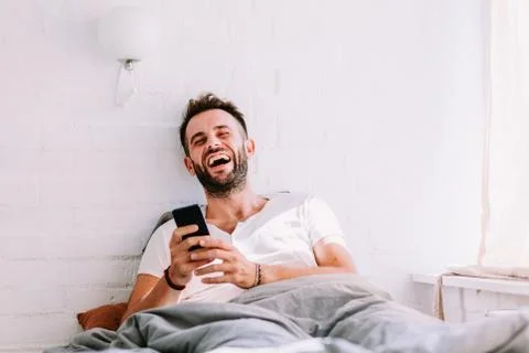 Young man using smartphone in the bed in the morning Stock Photos