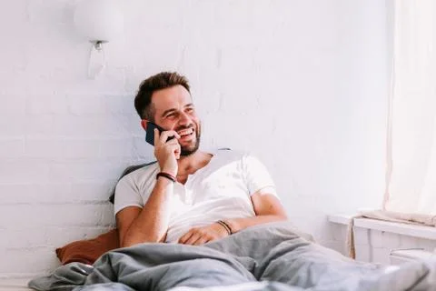 Young man using smartphone in the bed in the morning Stock Photos