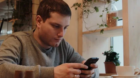 Young man using smartphone in a cafe Stock Footage 61863486
