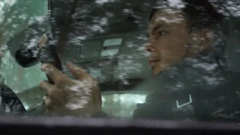 Young man using smartphone in a car. He is checking chats, news online 動画素材 122888994