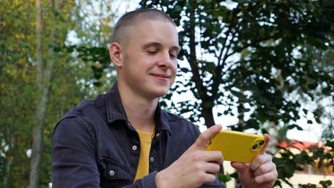 Young man using a smartphone communicates and poses for the camera in a public Foto stock