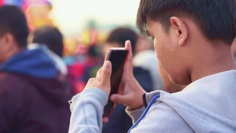Young man using smartphone at crowded outdoor festival, Stock Footage 333560179