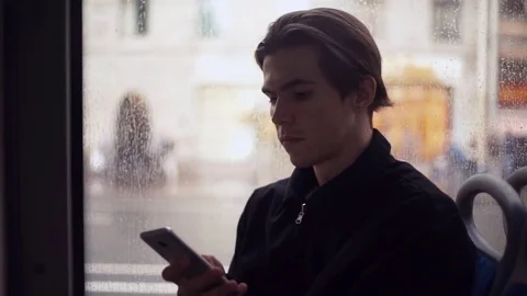 Young man using smartphone during bus ride. Rain outside the window Video stock 77168471
