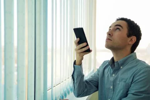 Young man using a smartphone in front of a window. Foto stock