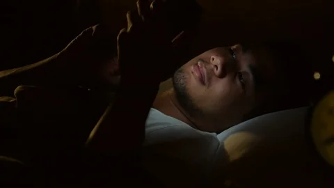 Young man using a smartphone in his bed at night . Stock Footage 125171676