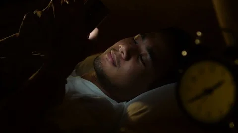 Young man using a smartphone in his bed at night . Stock Footage 125171688