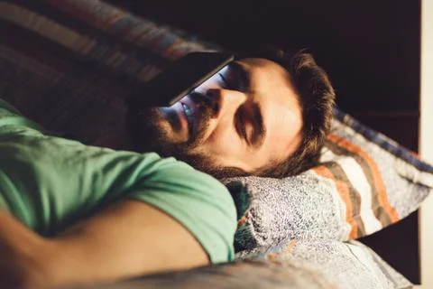 Young man using a smartphone in his bed Stock Photos