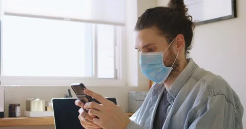 Young Man Using Smartphone in Home Office Wearing Medical Mask Stock Footage 127713233