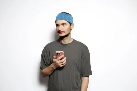 Young man using smartphone isolated on white background. Looking away. Stock Photos