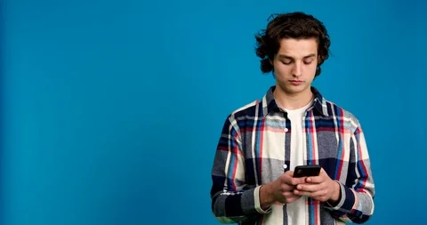 Young man using smartphone, looking away and shaking head isolated on blue Video stock 125838881
