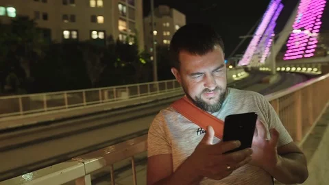 Young man using smartphone at night on the illuminating bridge, Jerusalem. Stock Footage 99310307