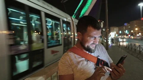 Young man using smartphone at night on the illuminating bridge, Jerusalem. Stock Footage 99310334