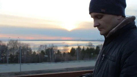 Young man using smartphone outdoor standing on roof bridge. Sunset cityscape Stock-Footage 75450630
